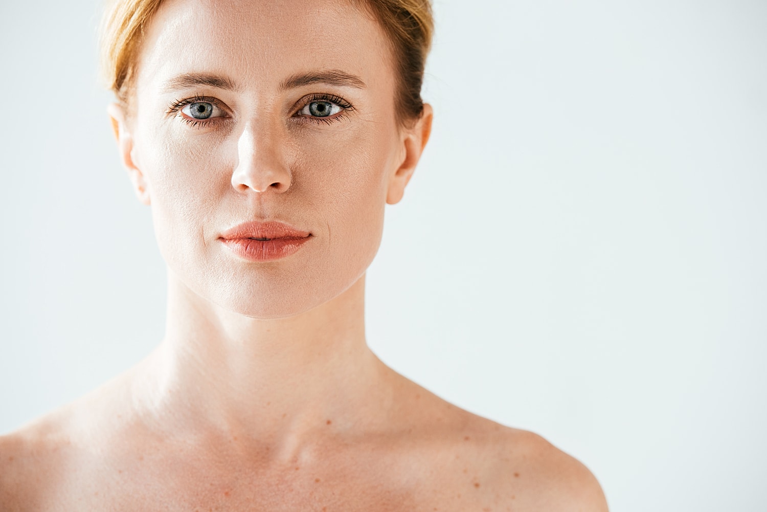 Woman in white top, profile against light background.