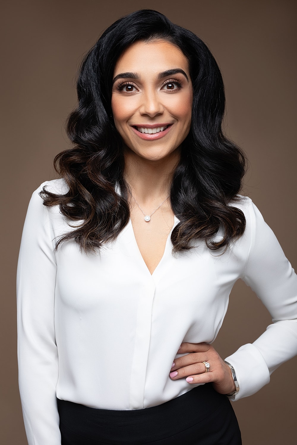 Smiling woman in white blouse with jewelry.