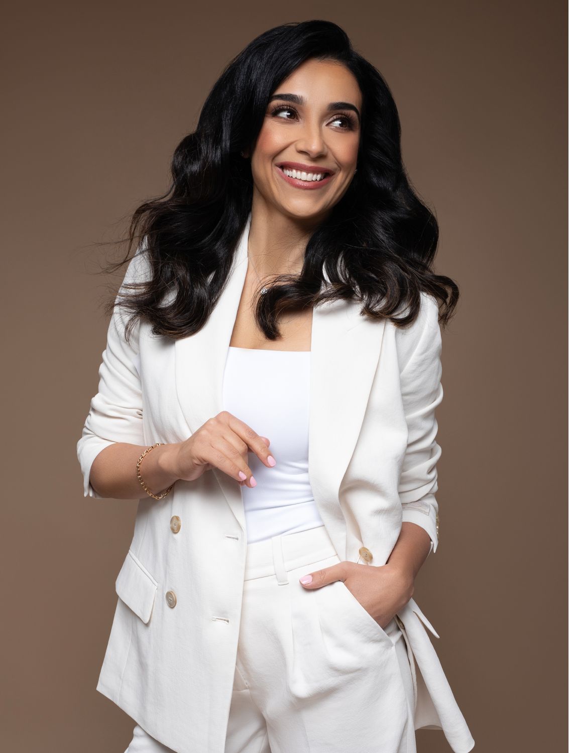 Smiling woman in stylish white suit against backdrop.