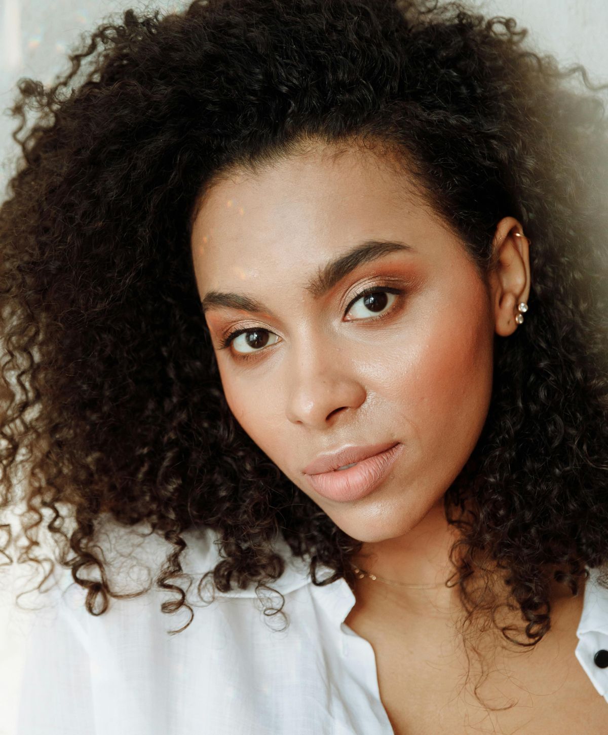 Person with curly hair and subtle makeup.