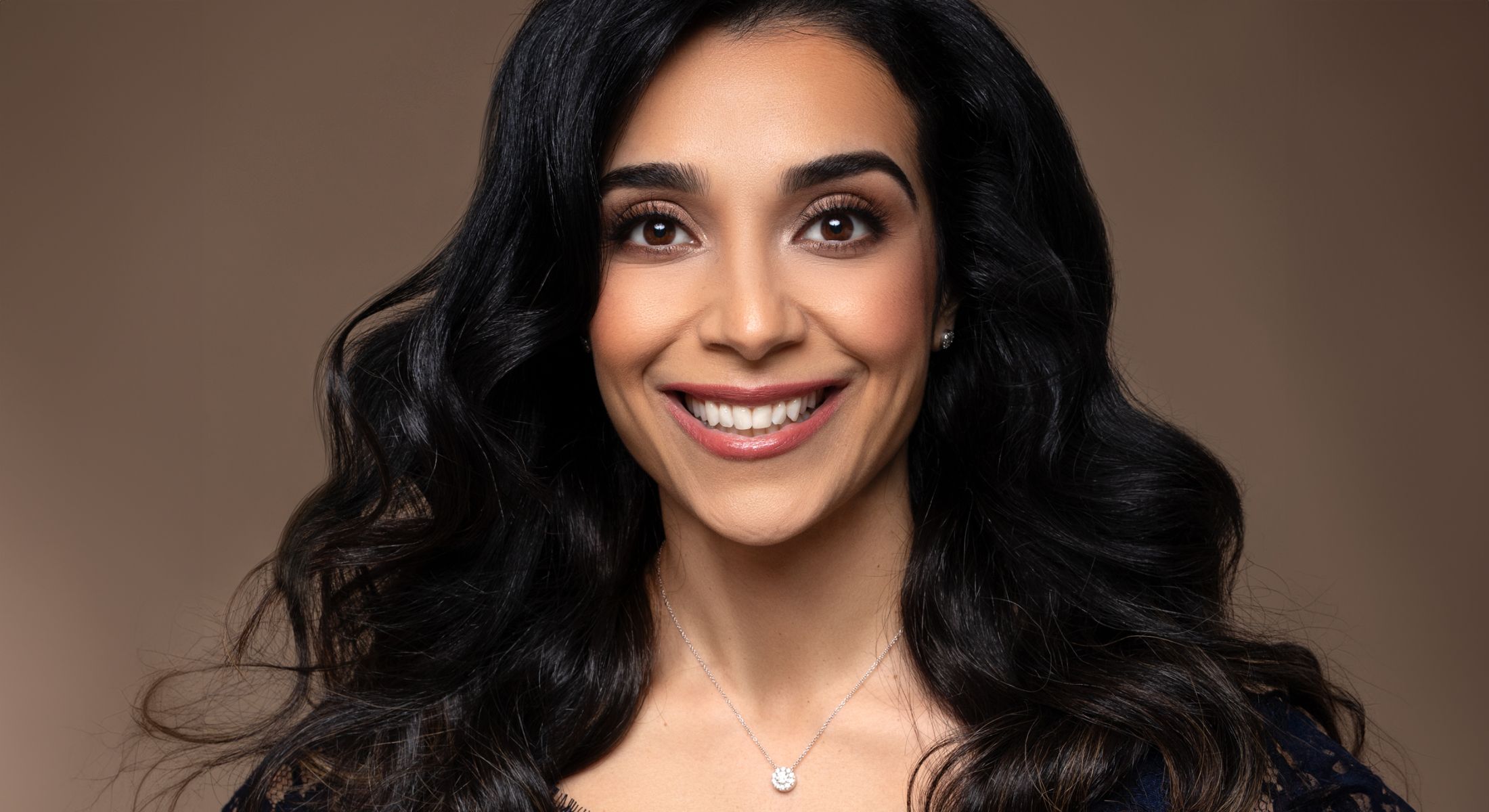 Smiling woman with long, wavy black hair.