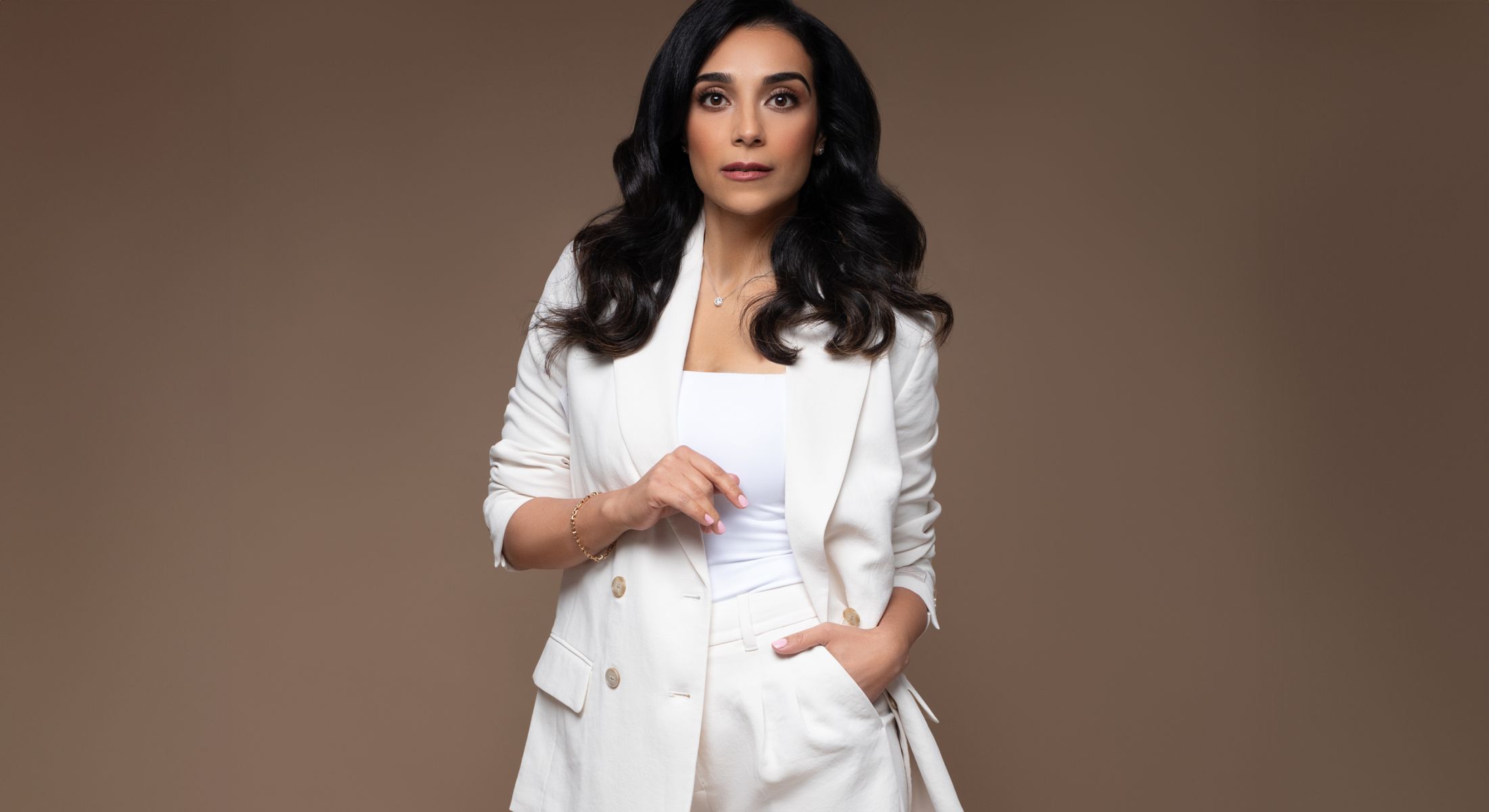 Woman in a stylish white suit posing confidently.